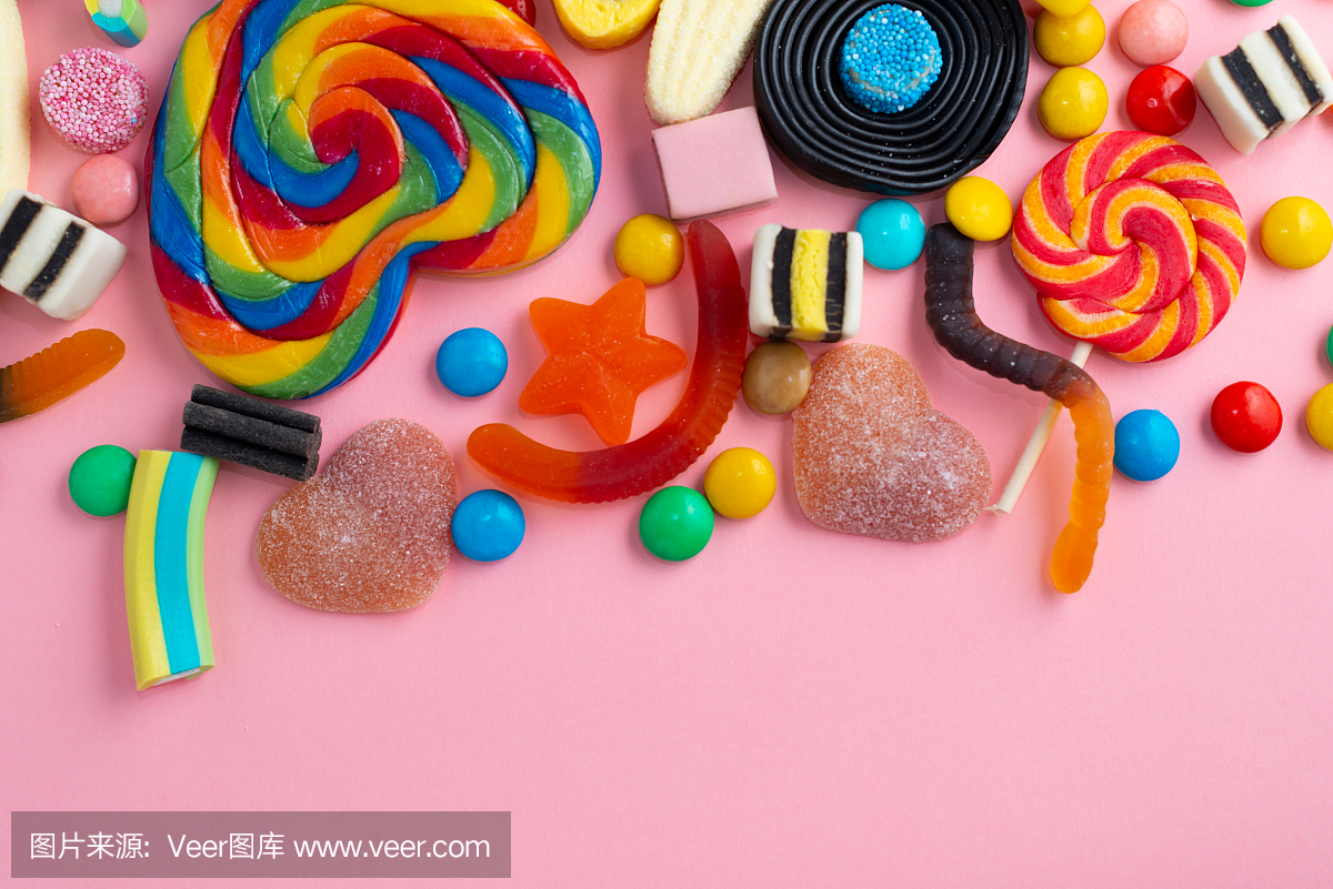 糖果和果冻彩色阵列不同的儿童糖果和糖果在粉红色的背景与复制空间